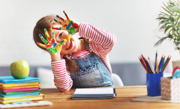 happy funny child girl draws laughing shows hands dirty with paint