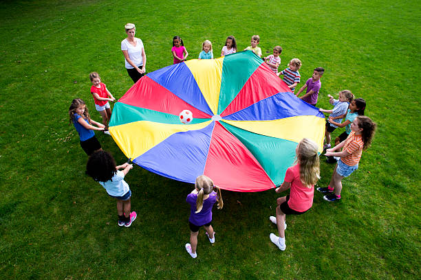 Children playing a game with a colourful Parachute